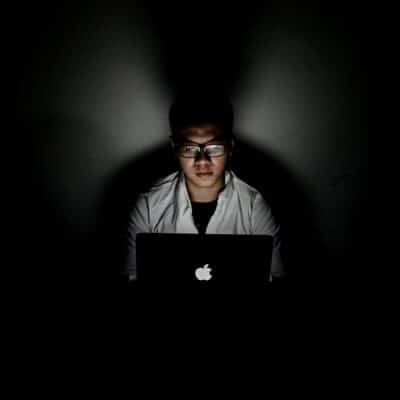 man using MacBook inside dark room